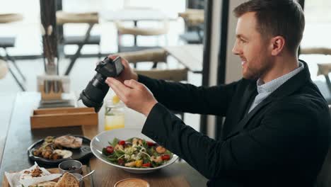 Stylish-young-man-takes-pictures-on-a-mirrorless-camera-dishes-at-the-table
