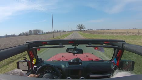 POV-while-a-couple-are-driving-on-a-country-road-with-roof-off-of-their-vehicle