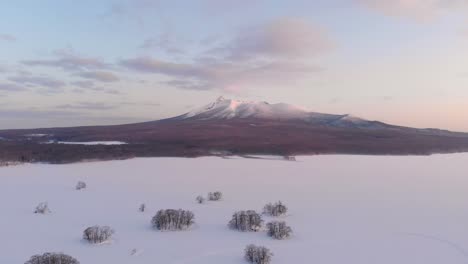 Slow-cinematic-aerial-dolly-out-above-frozen-lake-landscape-and-mountain