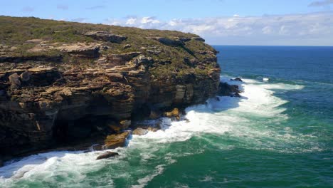 Wellen,-Die-Tagsüber-Auf-Die-Küstenklippen-Im-Royal-National-Park-In-New-South-Wales,-Australien,-Einschlagen---Luftdrohnenaufnahme