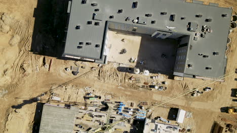 top-down-zoom-out-from-construction-site-with-building-crane-and-big-shadow-of-them