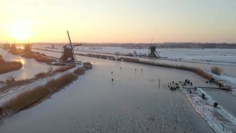 Bright-morning-sunlight-with-locals-ice-skating-on-river-at-Kinderdijk-Windmills