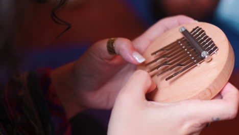 Close-up-shot-of-woman-playing-kalimba-instrument-during-sunny-day-on-Madeira-Island,Portugal