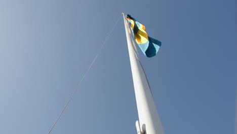 Man-raising-the-Swedish-flag-on-flag-pole-in-slow-motion,-summer-day
