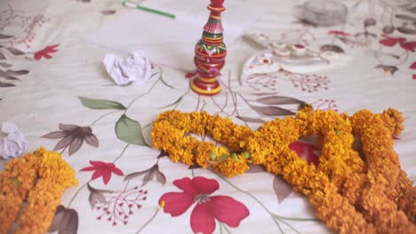 Garlands-of-marigold-flowers,-torn-papers-and-gaachkouto-on-bed,-Indian-wedding