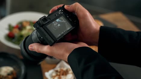 Close-up-of-a-male-hand-taking-a-picture-on-a-mirrorless-dish-on-the-table