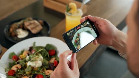 Close-up-of-smartphone-screen-taking-pictures-of-dishes-on-table