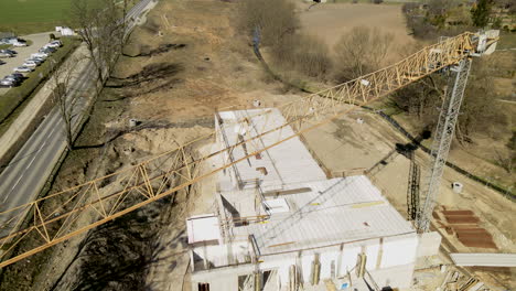 Aerial-drone-flight-over-crane-and-sandy-construction-site-in-countryside-during-sunny-day