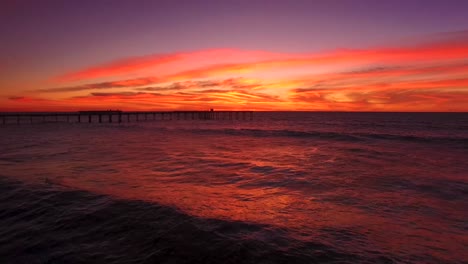 Aerial-4K-seascape-horizon-view-of-Ocean-Beach-pier-silhouette-during-a-colorful-golden-orange-sunset