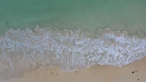 4K-Aerial-view-top-view-drone-move-beautiful-topical-beach-with-white-sand-and-water-surface-texture,-foamy-waves,-perfectly-clear-ocean-water-with-corals