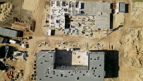 Aerial-top-down:-Sandy-construction-site-build-high-housing-blocks-during-sunny-day
