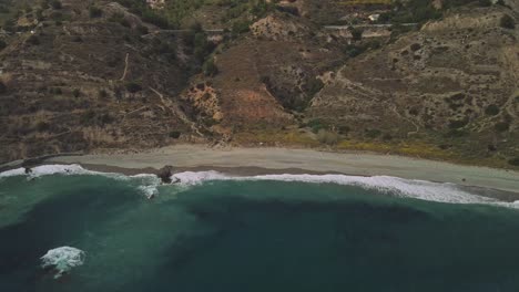 Drone-flying-sideways-at-the-coastline-of-Nerja,-South-of-Spain,-tilting-up-into-the-horizon