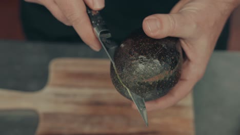 Close-up-on-hands-cutting-avocado-with-steel-knife