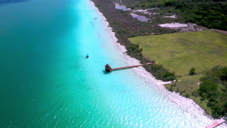 Rotating-drone-shot-of-piers,-docks-and-boat-in-turquoise-waters-at-Bacalar-Mexico