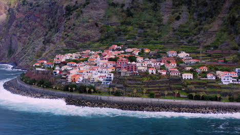 Aerial-flight-towards-idyllic-Portuguese-village-located-in-front-of-gigantic-mountain-and-blue-ocean-in-foreground