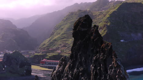 Aerial-orbiting-shot-of-gigantic-rock-formation-surrounded-by-mystic-mountains-and-atlantic-ocean-on-Madeira,Portugal