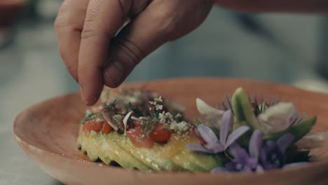 Hand-of-chef-putting-flowers-on-avocado-slices
