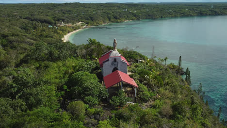 Aerial-view-around-the-Chapelle-Notre-Dame-de-Lourdes,-on-sunny-Lifou-island,-in-New-Caledonia---orbit,-drone-shot