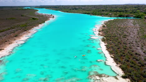 Descending-drone-shot-of-kayakers-in-clear-blue-waters-at-Bacalar-Mexico