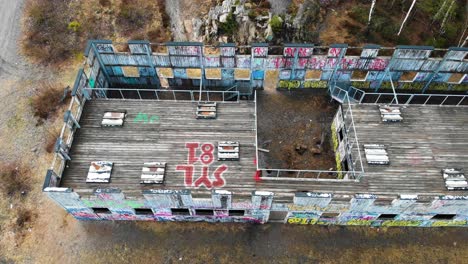 Aerial-top-down-showing-old-wooden-paintball-building-with-graffiti-in-wilderness