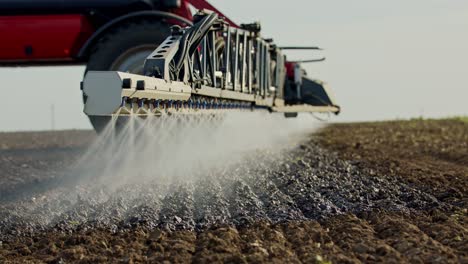 Close-up-of-a-farmer-spraying-soil-on-an-agricultural-campaign-from-a-red-machinery