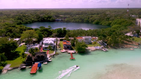 Drone-shot-of-homes-and-jet-skier-at-Bacalar-Mexico-with-a-small-pond-or-lagoon-in-the-background