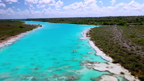 Revealing-drone-shot-of-Kayakers-in-the-clear-blue-waters-at-Bacalar-Mexico