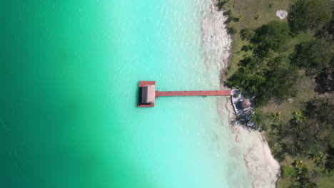 Downward-angle-drone-shot-of-pier,-hut-and-turquoise-color-water-in-Bacalar-Mexico