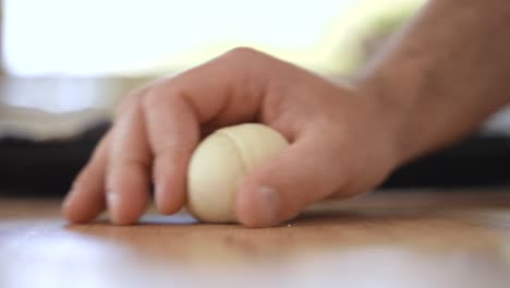 Making-Round-Dough-Shape,-Rolling-it-on-Table-with-Hand,-Close-Up-in-Slow-Motion