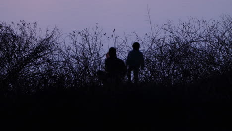Silhouetted-Image-Of-Father-And-Son-Fishing-With-A-Net-On-The-River-At-Dusk-In-Tokyo,-Japan