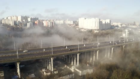 Niebla-Espesa-Sobre-La-Carretera-Principal,-Tiro-De-Dron-De-Smog-Y-Contaminación-Colgando-Sobre-Chisinau,-Moldavia