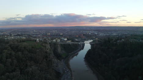 A-profile-aerial-shot-of-Clifton-suspension-bridge-looking-along-the-River-Avon-and-gorge-toward-the-city-of-Bristol-at-sunset