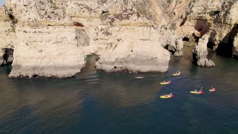 Aerial-shot-flying-over-people-kayaking-on-the-coast-of-Lagos-in-Portugal