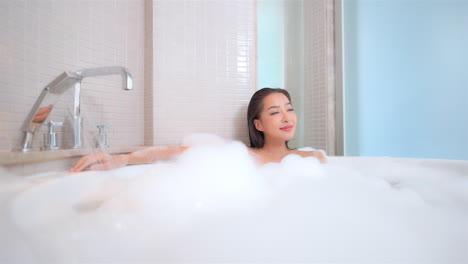 Pretty-asian-woman-in-full-foamy-bathtub-enjoying-and-relaxing,-lavish-lifestyle-concept,-full-frame