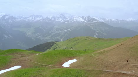 Antena:-Alpes-Europeos,-Telón-De-Fondo-De-Montañas-Nevadas-Con-Excursionistas-En-Primer-Plano