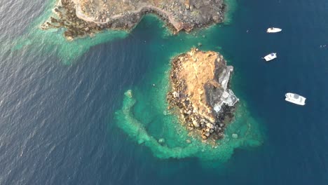 Video-De-Vista-Aérea-De-Drones-De-Hermosos-Barcos-Navegando-En-El-Mar-Egeo-Azul-Profundo-Durante-La-Puesta-De-Sol,-Santorini,-Grecia