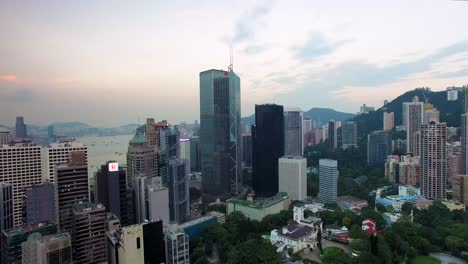 Vista-Aérea,-Distrito-Central-De-Hong-Kong,-Rascacielos-Y-Edificios-Bajo-Un-Cielo-Nublado-En-El-Crepúsculo,-Tire-Hacia-Atrás-Del-Tiro-Del-Dron