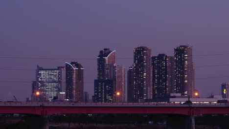 Verkehr-Auf-Der-Hochstraße-Mit-Beleuchteten-Hochhäusern-In-Der-Metropole-Tokio,-Japan-In-Der-Abenddämmerung
