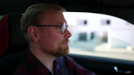 Caucasian-Man-with-Glasses,-Drives-Car-and-Talks,-Close-Up-from-Side