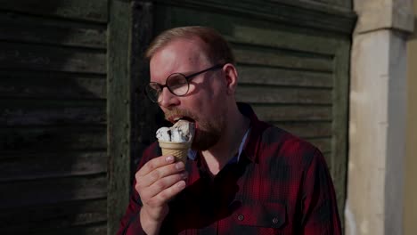 Young-Man-with-Glasses-Eats-Ice-Cream-in-Cone,-Sunny-Day-Outside