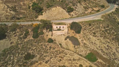 Drone-moving-backwards-from-an-abandoned-house-near-the-rocky-coast