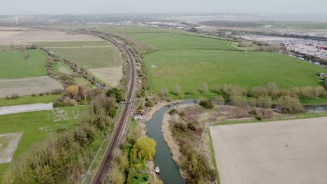 Aerial-drone-shot-of-train-tracks-along-the-River-Stour-in-Kent,-England