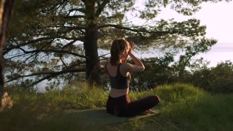 Caucasian-girl-namaste-yoga-pose-in-forest-at-morning-summer-sunrise