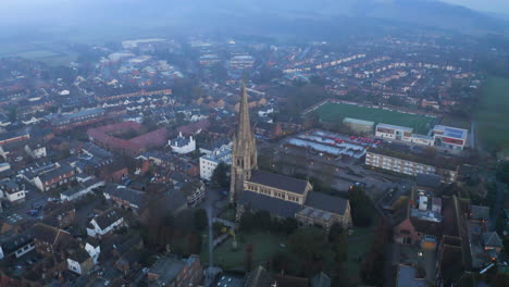 An-aerial-shot-flying-above-an-old-English-church-in-Dorking,-Surrey-on-a-misty-morning