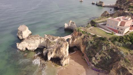 Aerial-view-of-pont-romain-de-Lagos,-rock-arch-bridge-at-Praia-dos-Estudantes-Algarve,-Portugal