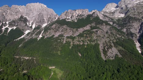 Maravillosas-Montañas-En-Los-Alpes-Albaneses-Con-La-Parte-Superior-Cubierta-De-Nieve-Y-árboles-Verdes