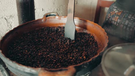 Die-Hand-Der-Frau-Röstet-Kaffee-In-Einem-Großen-Topf-In-Guatemala,-Mittelamerika---Nahaufnahme