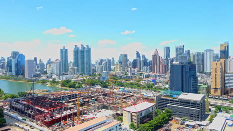 Time-lapse-of-Queen-Sirikit-National-Convention-Centre-construction-site-near-Benjakitti-Park-and-Lake,-Millenium-Residence-Apartment,-CTI-Tower,-Ocean-Tower-in-Bangkok,-cloudscape-on-a-sunny-day