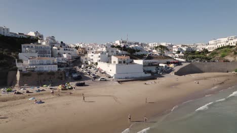 Cinematic-aerial-panning-view-of-Burgau-beach-and-whitewashed-buildings,-Algarve-Portugal