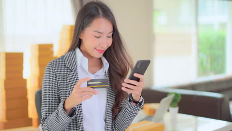 A-young-woman-double-checks-the-number-of-her-credit-card-against-her-smartphone-entry